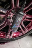 Wheel Cleaner Bleeding – Black bottle leaning against multi-spoke alloy wheel covered in dark purple-red bleeding iron reaction | Car Detailing | miio Store
