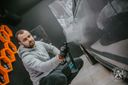 Quick Detailer 500ml – Man in grey hoodie low-angle view applying product to silver car door with black glove in detailing studio | Car Detailing | miio Store
