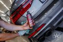 Ceramic Shampoo 500ml – Main tenant flacon près du feu arrière voiture sombre avec chiffon microfibre bleu visible | Lavage Auto | miio Store