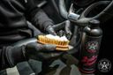 Alcantara Cleaner – Black gloved hand using natural boar bristle brush to agitate alcantara surface, product bottle alongside | Car Interior | miio Store