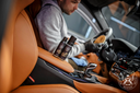 Leather Care Set – Detailer em jaqueta cinza a aplicar produto com escova em luxuoso assento de couro caramelo | Cuidado do Couro | miio Store