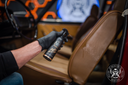 Leather Quick Detailer – Close-up de mão com luva preta com frasco junto ao couro caramelo, rótulo dourado visível | Cuidado do Couro | miio Store