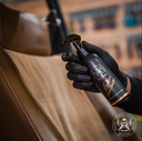 Leather Quick Detailer – Mão com luva preta a pulverizar produto em assento de couro bege | Cuidado do Couro | miio Store