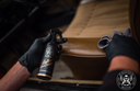 Leather Quick Detailer – Mão com luva a segurar frasco junto ao painel interior de couro caramelo | Cuidado do Couro | miio Store